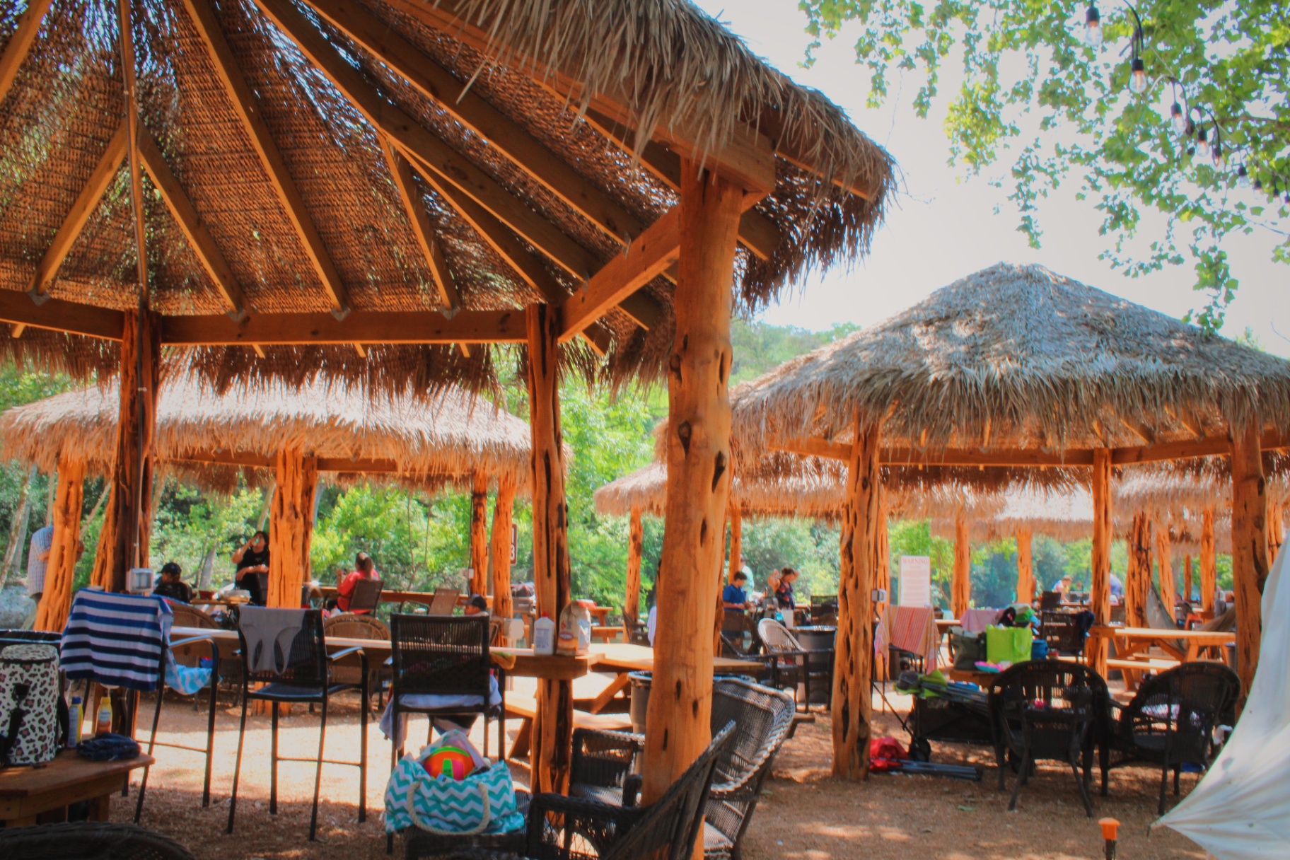 Multiple thatched-roof cabanas with guests