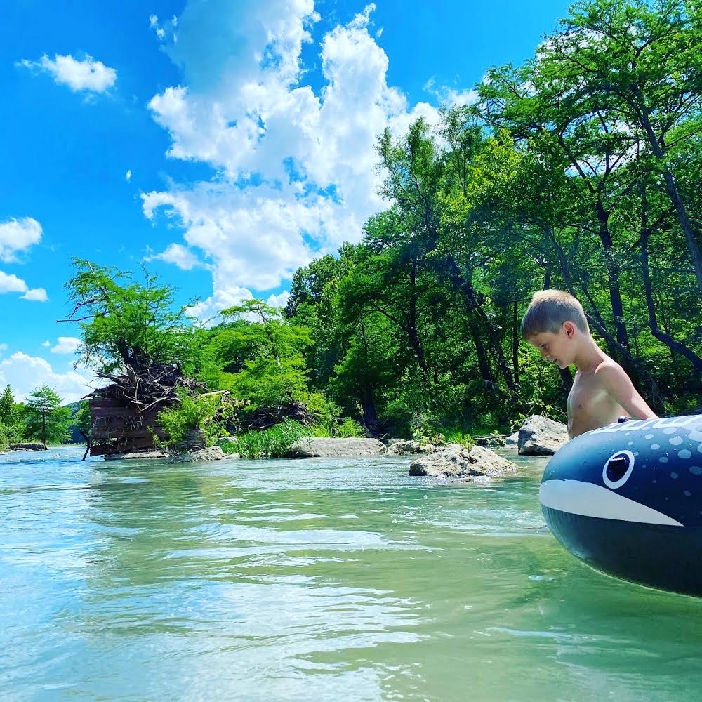 Kid floating on a whale float in the river