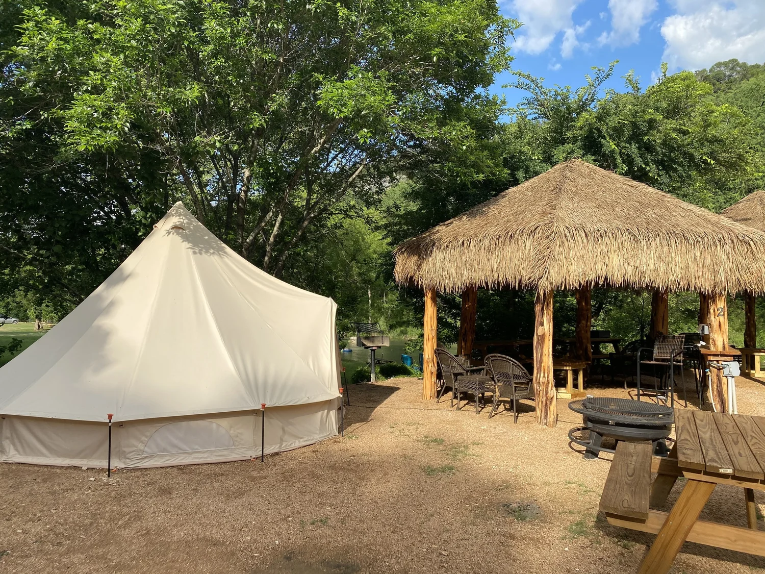 Bell tent with tiki cabana and fire pit during the day